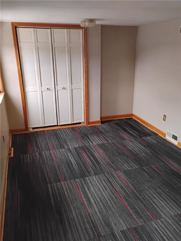 unfurnished bedroom featuring dark colored carpet and a closet