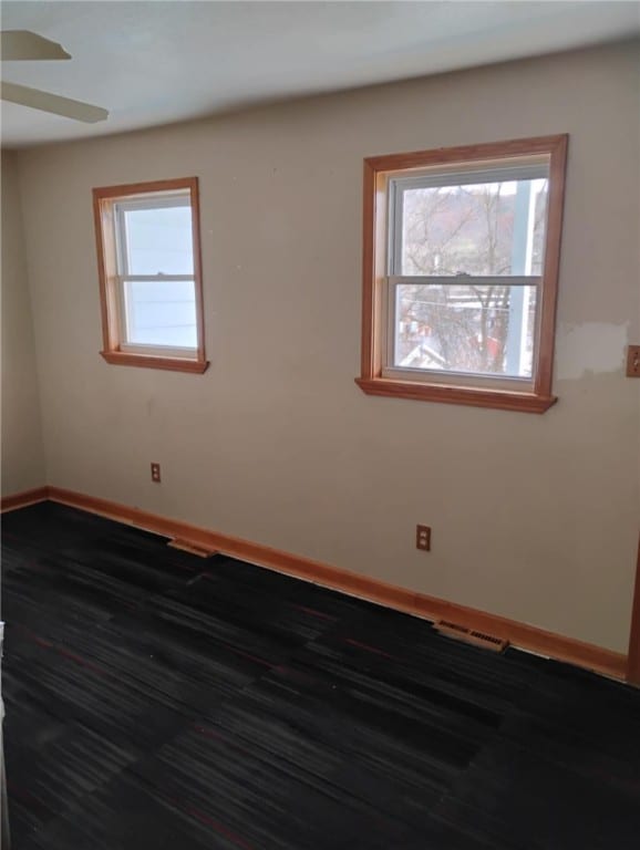 empty room with ceiling fan and dark hardwood / wood-style floors