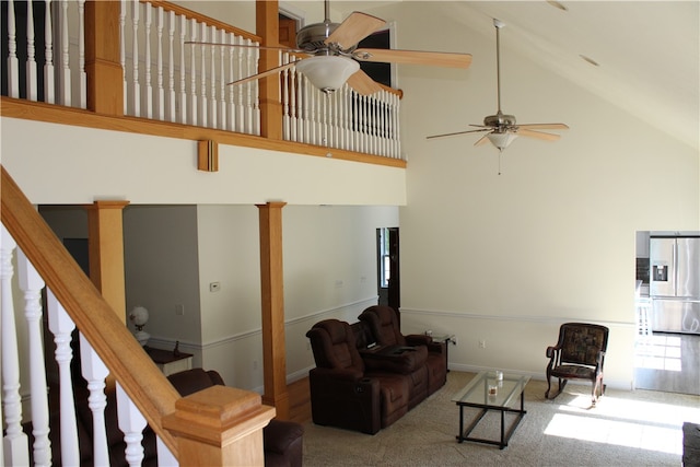 carpeted living room with ceiling fan and high vaulted ceiling