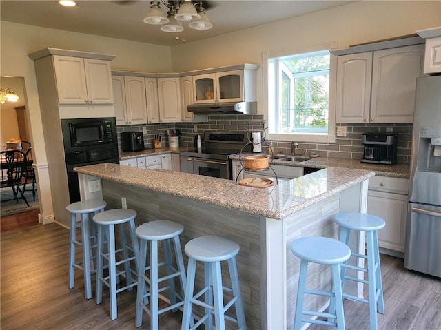 kitchen with light hardwood / wood-style floors, a notable chandelier, white cabinetry, a kitchen bar, and appliances with stainless steel finishes