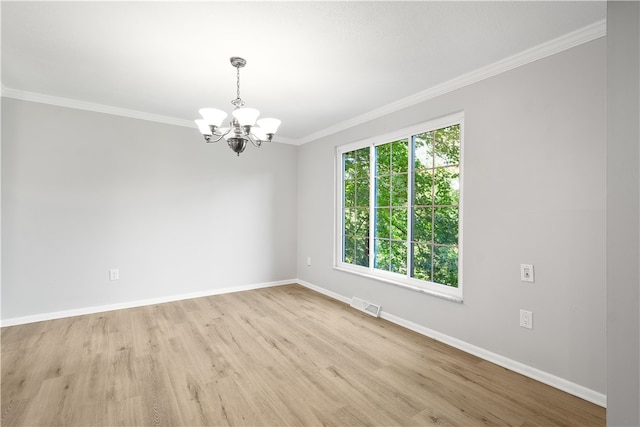 spare room with light wood-type flooring, ornamental molding, and a chandelier