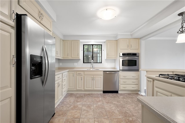 kitchen featuring light tile patterned flooring, decorative light fixtures, stainless steel appliances, and cream cabinetry