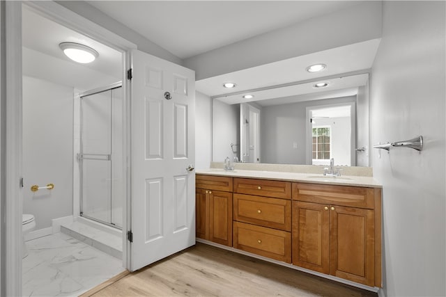 bathroom featuring wood-type flooring, toilet, a shower with door, and vanity