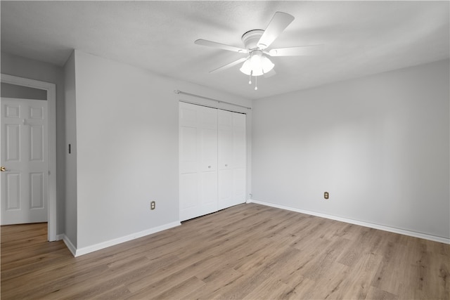 unfurnished bedroom featuring ceiling fan, a closet, and light wood-type flooring