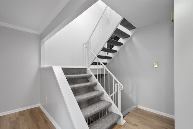 stairs with ornamental molding and hardwood / wood-style floors