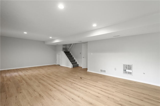 basement featuring light wood-type flooring and heating unit