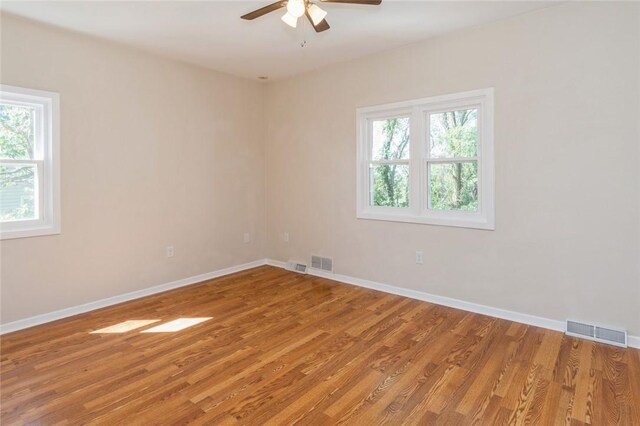 unfurnished room with a wealth of natural light, ceiling fan, and hardwood / wood-style flooring