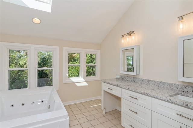 bathroom with tile patterned flooring, vanity, a bathing tub, and lofted ceiling with skylight