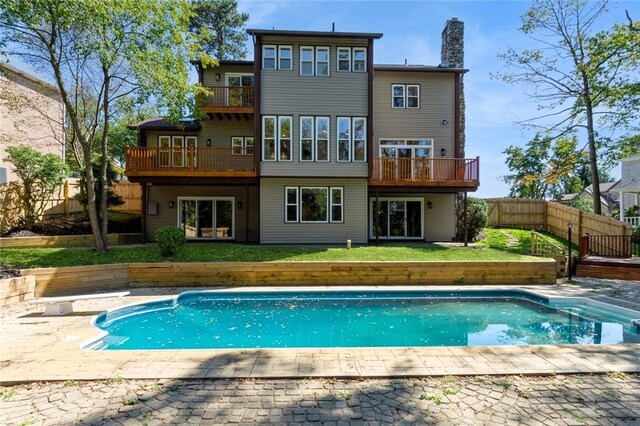 back of property featuring a balcony, a fenced in pool, a lawn, and a patio area