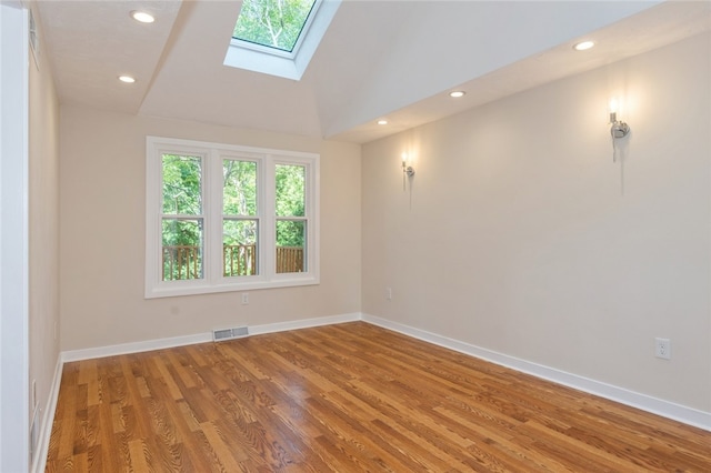 unfurnished room featuring hardwood / wood-style flooring and lofted ceiling with skylight