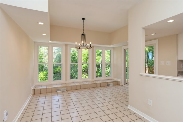 empty room with a chandelier, a wealth of natural light, and light tile patterned floors