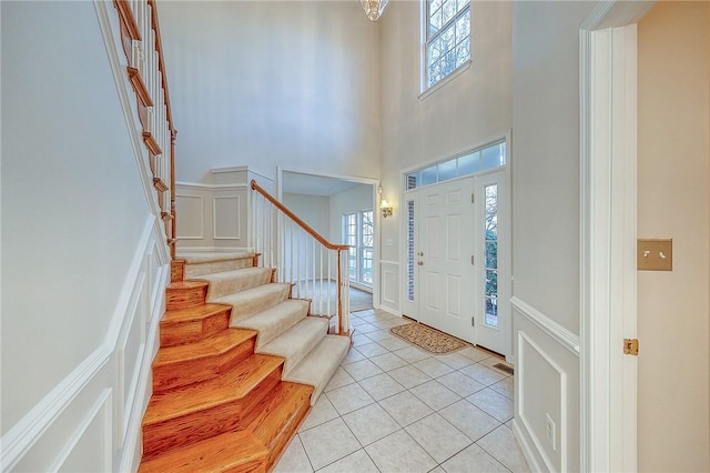 entrance foyer with a towering ceiling, a healthy amount of sunlight, and light tile patterned floors