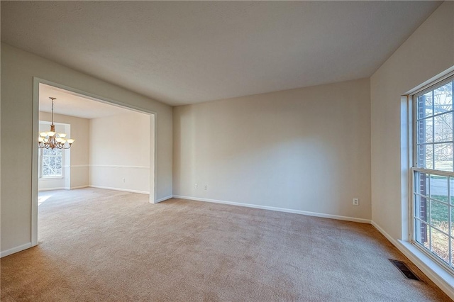 carpeted spare room featuring a chandelier