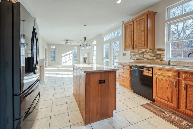 kitchen with black appliances, a kitchen island, a healthy amount of sunlight, and hanging light fixtures