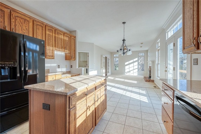 kitchen featuring a center island, dishwasher, hanging light fixtures, black refrigerator with ice dispenser, and a chandelier