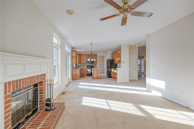 unfurnished living room with ceiling fan, light colored carpet, and a fireplace