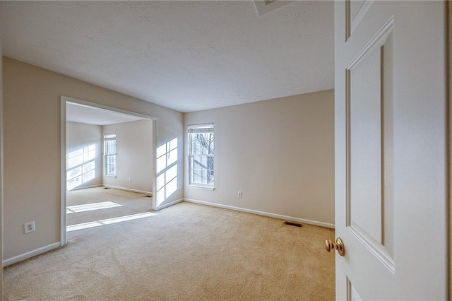 empty room with light carpet and a textured ceiling