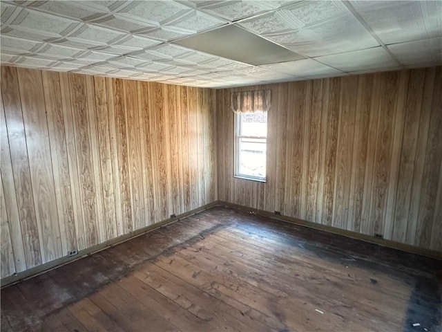 unfurnished room with wooden walls and dark wood finished floors