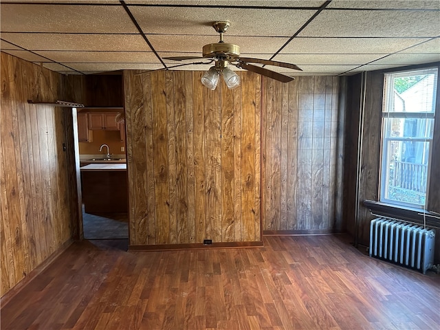 empty room with radiator, a paneled ceiling, ceiling fan, and dark wood-type flooring