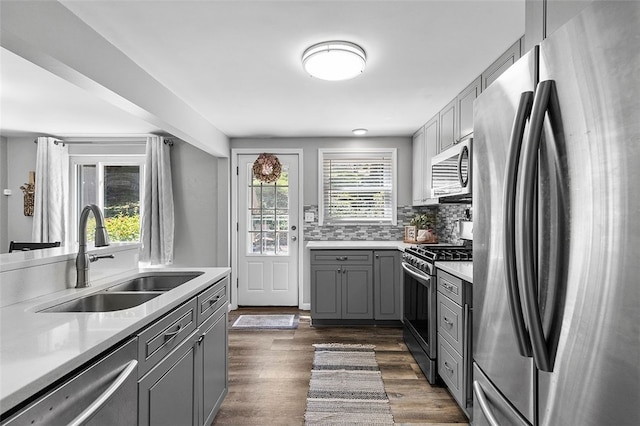 kitchen with gray cabinetry, dark hardwood / wood-style floors, tasteful backsplash, stainless steel appliances, and sink