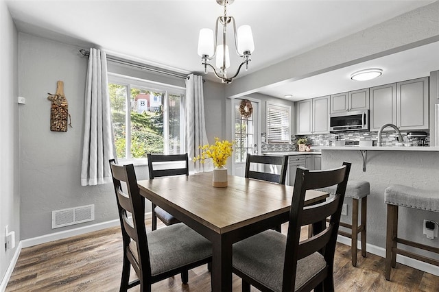 dining space with hardwood / wood-style floors, a chandelier, and sink