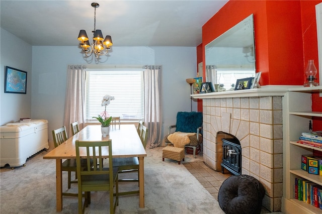 carpeted dining room featuring a tiled fireplace and an inviting chandelier