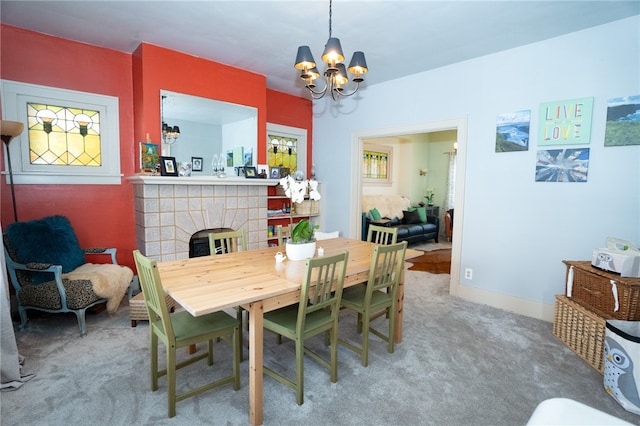 carpeted dining space featuring a tiled fireplace and an inviting chandelier