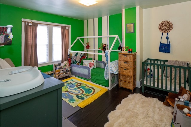 bedroom with dark hardwood / wood-style flooring and a crib