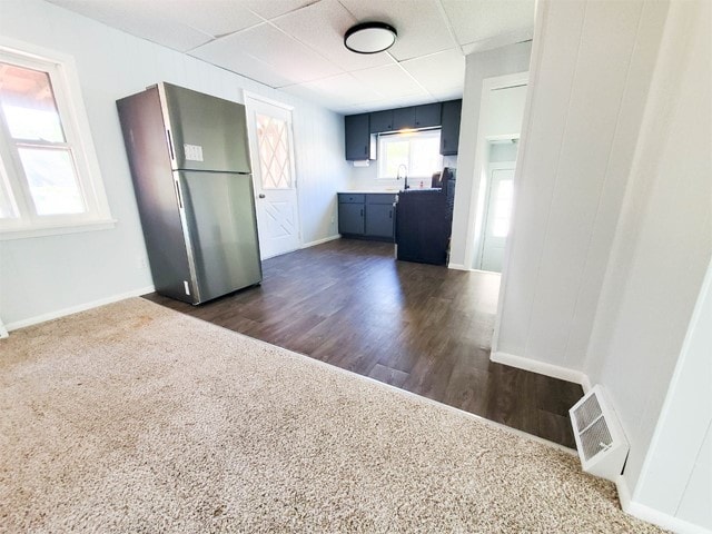 kitchen with dark wood-type flooring, stainless steel refrigerator, sink, and a drop ceiling