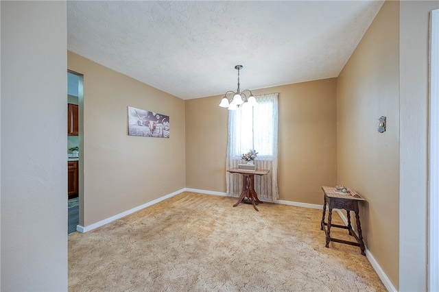 unfurnished room featuring a notable chandelier, light colored carpet, and a textured ceiling