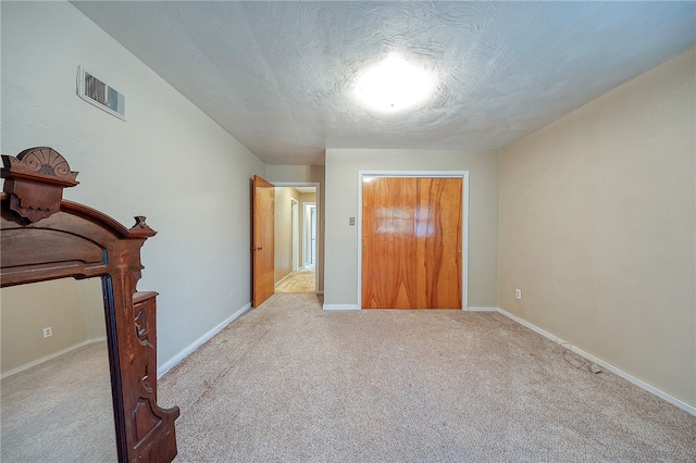 unfurnished bedroom with a closet, light colored carpet, and a textured ceiling