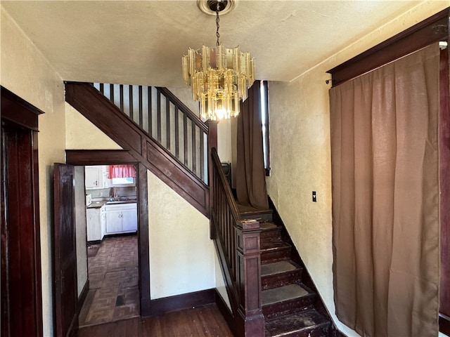 staircase with wood-type flooring and an inviting chandelier