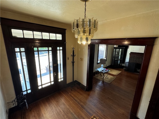 entryway featuring dark wood-type flooring, a textured ceiling, and an inviting chandelier