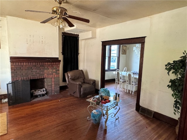 living room featuring dark wood-type flooring, ceiling fan, and a brick fireplace