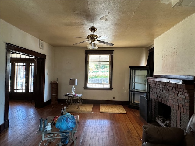 unfurnished living room with a fireplace, a textured ceiling, ceiling fan, and dark hardwood / wood-style floors