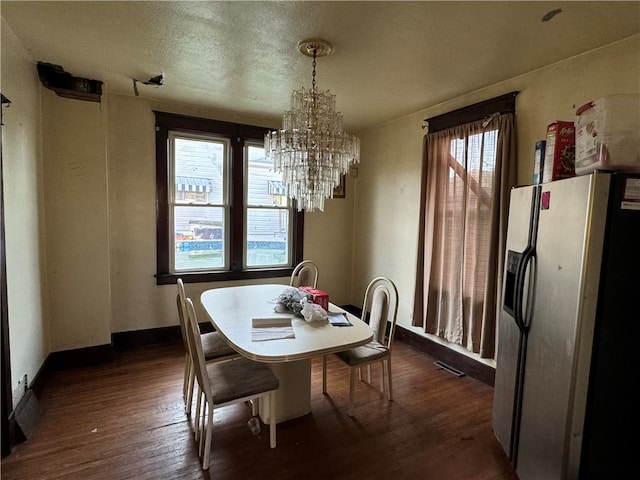 dining area with dark hardwood / wood-style flooring, a notable chandelier, and a textured ceiling