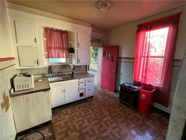 kitchen with white cabinets, dark parquet floors, and sink