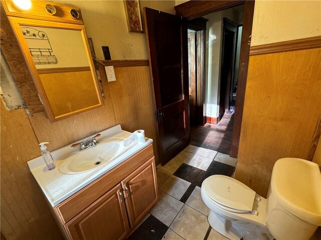 bathroom with vanity, toilet, wood walls, and tile patterned floors