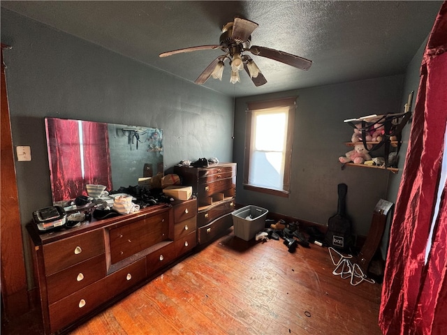 bedroom featuring ceiling fan, wood-type flooring, and a textured ceiling