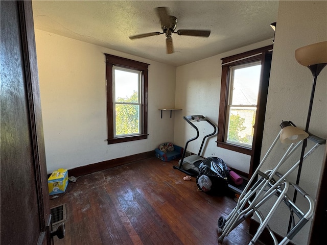 workout room with ceiling fan, hardwood / wood-style flooring, and a textured ceiling