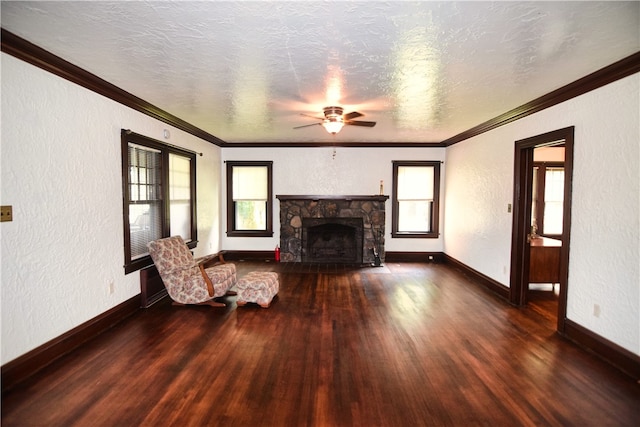 unfurnished living room with dark wood-type flooring, ceiling fan, a wealth of natural light, and a stone fireplace