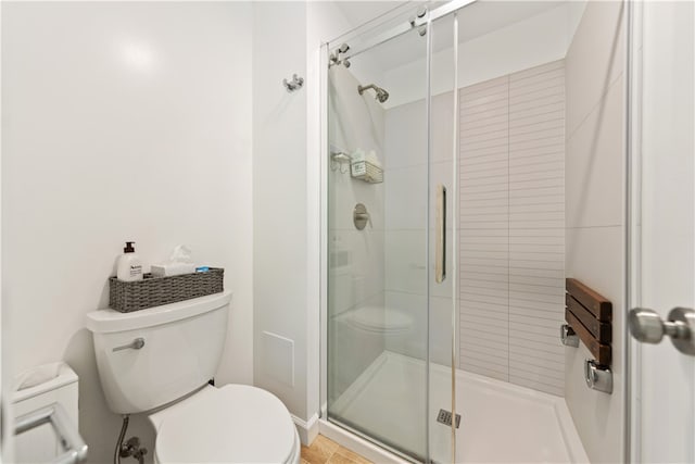 bathroom featuring toilet, hardwood / wood-style floors, and a shower with shower door