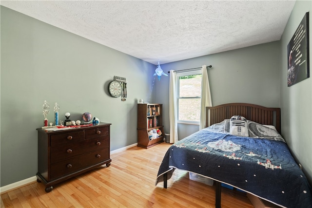 bedroom featuring a textured ceiling and light hardwood / wood-style flooring