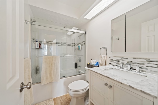 full bathroom with enclosed tub / shower combo, hardwood / wood-style floors, backsplash, toilet, and vanity