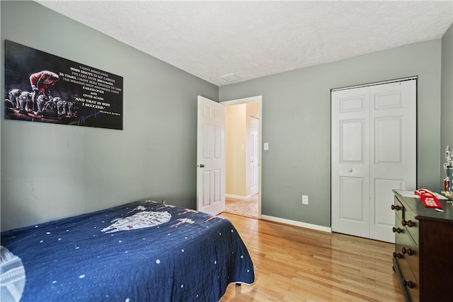 bedroom with a closet, hardwood / wood-style floors, and a textured ceiling