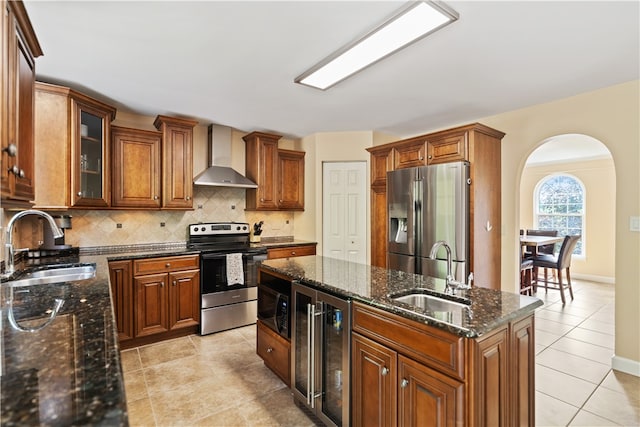 kitchen with appliances with stainless steel finishes, sink, beverage cooler, and wall chimney range hood