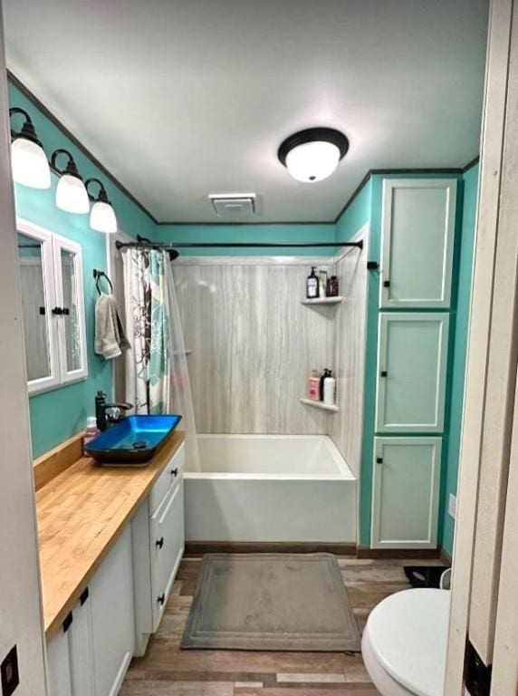 full bathroom with wood-type flooring, vanity, shower / tub combo, and toilet