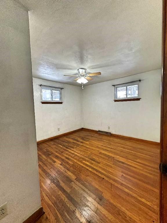 empty room featuring plenty of natural light, dark hardwood / wood-style floors, a textured ceiling, and ceiling fan