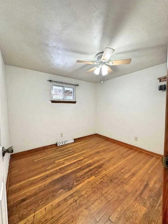 empty room featuring ceiling fan, hardwood / wood-style floors, and a textured ceiling