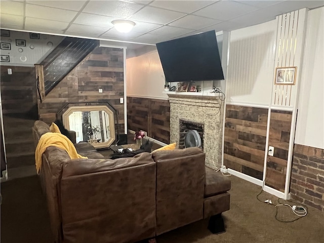 living room with wood walls, a drop ceiling, and carpet floors